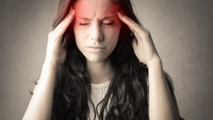 "Woman experiencing a tension headache caused by desk job stress, pressing her temples with visible discomfort